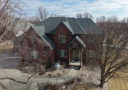 Aerial view of a large brick house showcasing a newly installed modern roof.