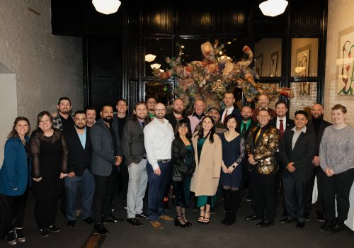A diverse group of people gather for a formal event in a stylish room.