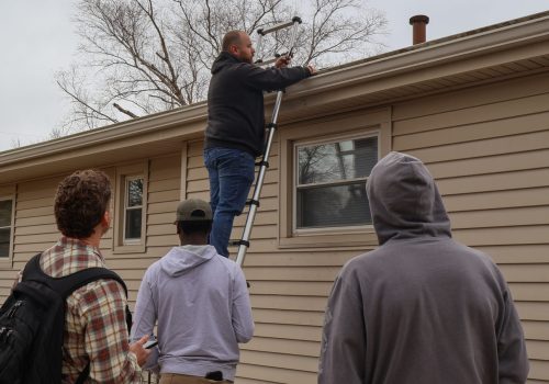 Roof inspection by a team of workers and a supervisor using a ladder.
