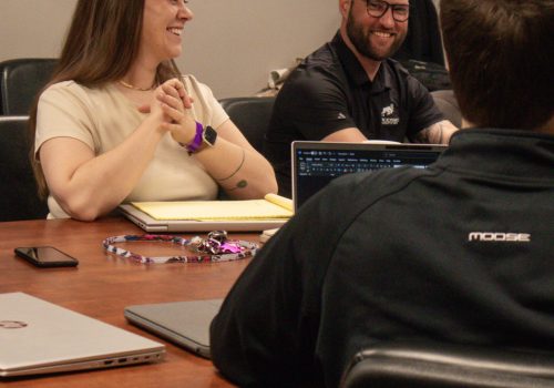Team members engaged in a positive meeting at a roofing business office.