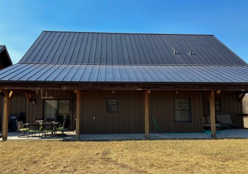 Metal roof on a wooden house showing landscaped backyard in clear daylight.