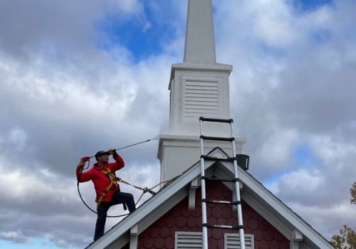 Professional roofer working on a steep church roof with safety equipment.